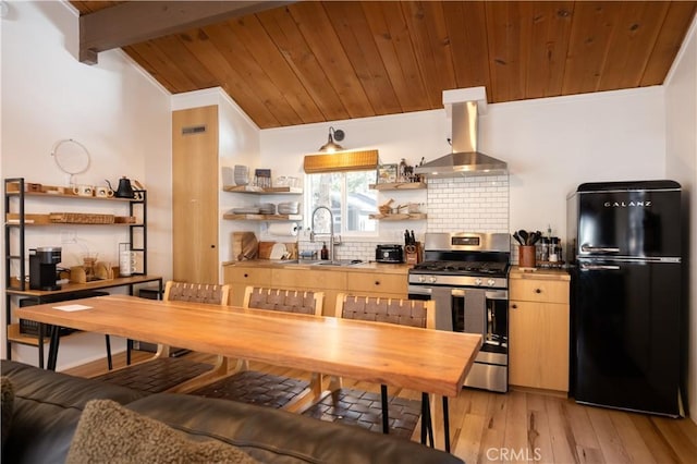 kitchen with stainless steel gas stove, decorative backsplash, freestanding refrigerator, open shelves, and exhaust hood