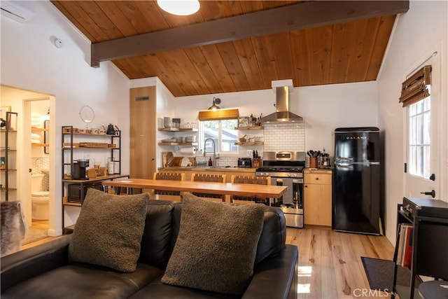 kitchen with a healthy amount of sunlight, freestanding refrigerator, stainless steel gas stove, wall chimney exhaust hood, and tasteful backsplash