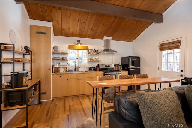 kitchen with open shelves, freestanding refrigerator, a sink, gas range, and wall chimney exhaust hood