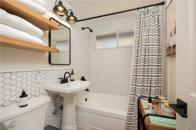 bathroom with shower / bath combo, a sink, tile walls, and toilet