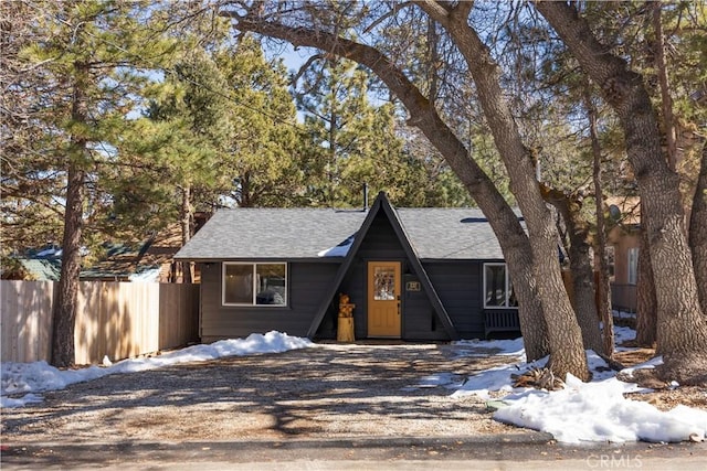 a-frame home with driveway, a shingled roof, and fence