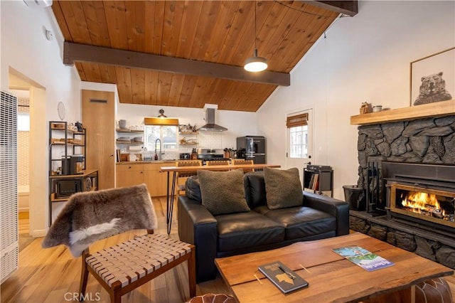 living area featuring high vaulted ceiling, a stone fireplace, wood ceiling, beam ceiling, and light wood finished floors