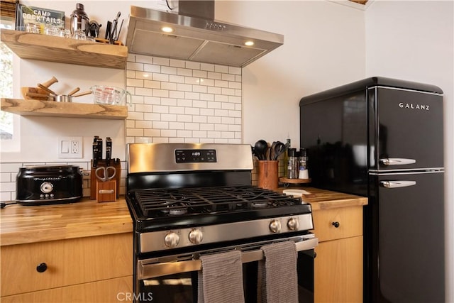 kitchen with open shelves, stainless steel gas range, freestanding refrigerator, ventilation hood, and butcher block countertops