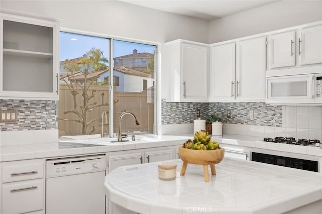 kitchen featuring white appliances, white cabinets, tile countertops, and backsplash