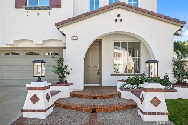 doorway to property featuring a garage, a tile roof, and stucco siding