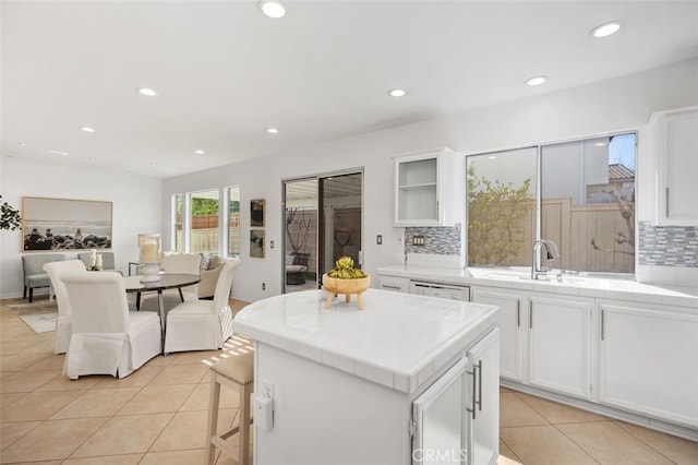 kitchen featuring tile countertops, light tile patterned floors, white cabinetry, and a sink