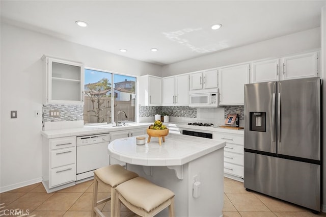 kitchen with tile countertops, white appliances, light tile patterned floors, and white cabinetry