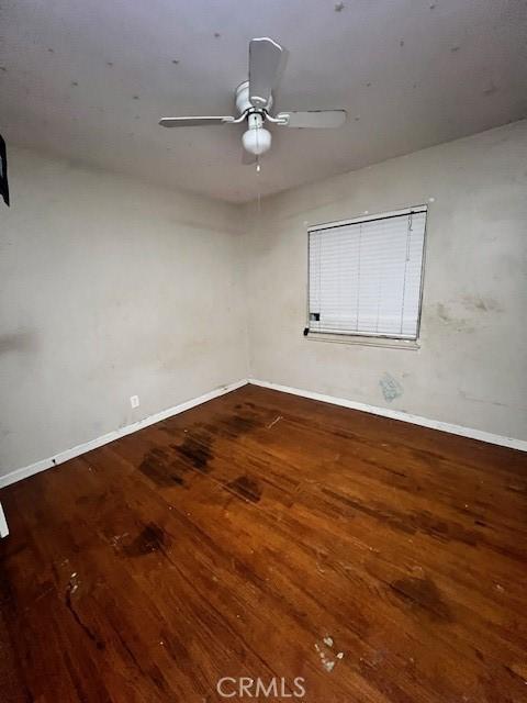 unfurnished room featuring ceiling fan, baseboards, and wood finished floors