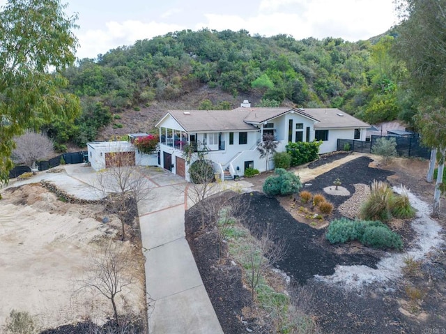 ranch-style house with a garage, fence, driveway, stairway, and a forest view