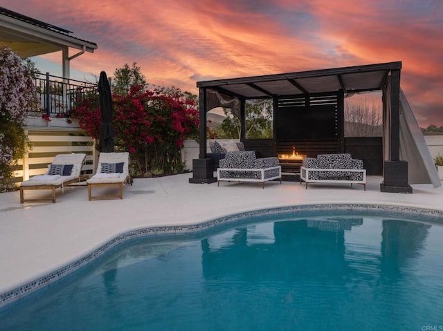 pool at dusk featuring an outdoor pool, a patio, and an outdoor hangout area