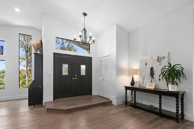 foyer featuring plenty of natural light, baseboards, wood finished floors, and an inviting chandelier