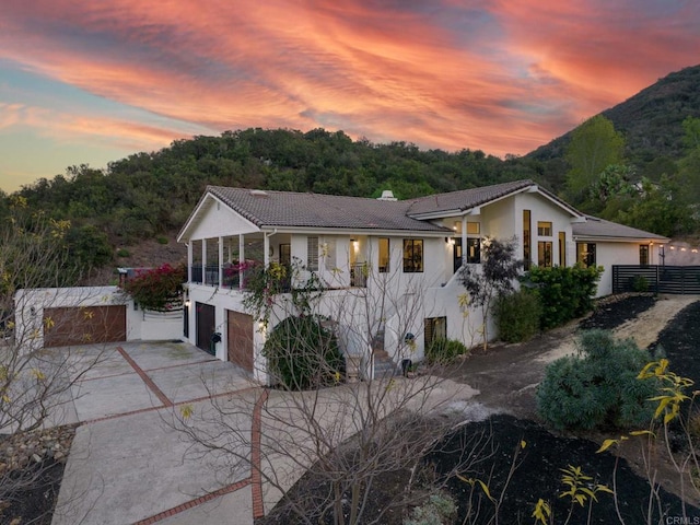 view of front facade with stucco siding, a tile roof, driveway, a mountain view, and a garage