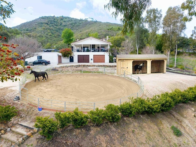 view of property's community featuring an exterior structure, an outbuilding, an enclosed area, a mountain view, and a garage