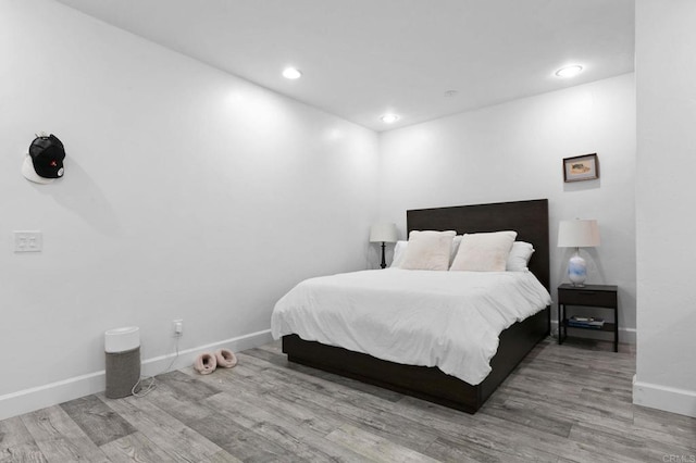 bedroom featuring baseboards, wood finished floors, and recessed lighting