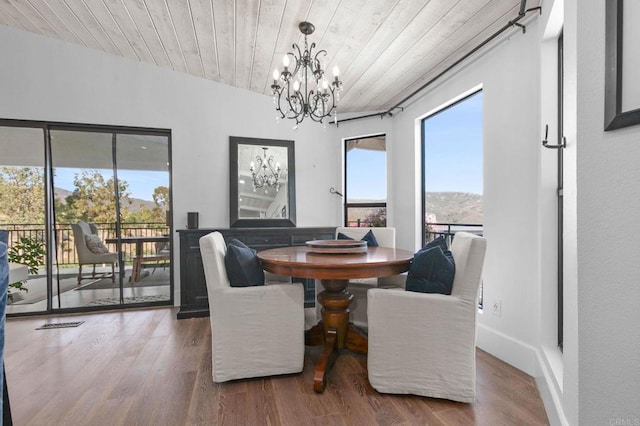 dining space featuring wood ceiling, wood finished floors, a chandelier, and a mountain view