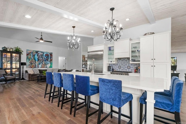 kitchen featuring beam ceiling, tasteful backsplash, white cabinetry, built in refrigerator, and wood ceiling