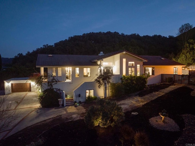 view of front facade with fence, driveway, and stucco siding
