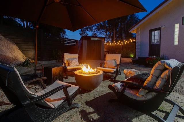 view of patio / terrace with a fenced backyard, an outdoor fire pit, an outbuilding, and a shed