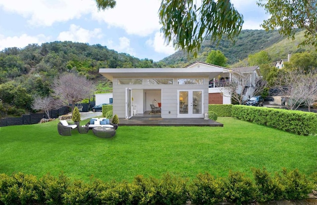 rear view of house featuring a lawn, fence, a deck, and french doors