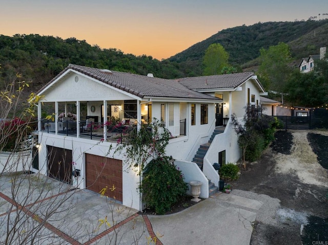 view of front of property with stucco siding, an attached garage, a mountain view, and a tiled roof
