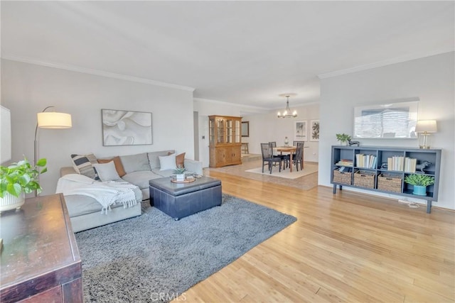 living area featuring an inviting chandelier, crown molding, and wood finished floors