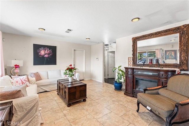 living room with baseboards, visible vents, and a glass covered fireplace