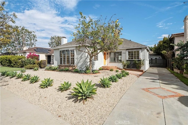 ranch-style home with fence, concrete driveway, a gate, stucco siding, and a chimney