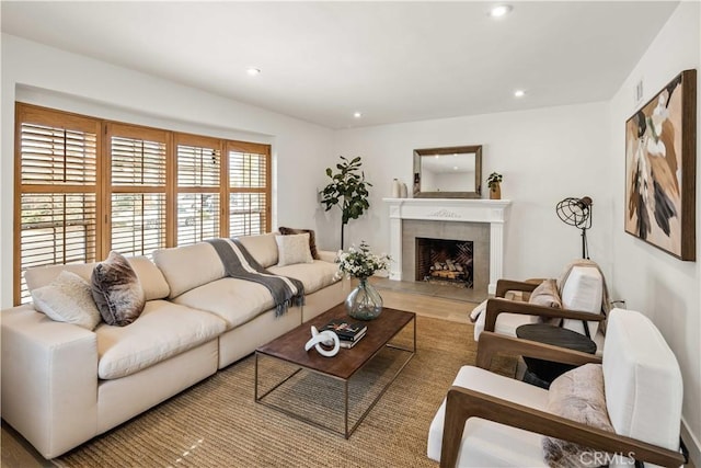 living area featuring a fireplace with raised hearth, wood finished floors, and recessed lighting