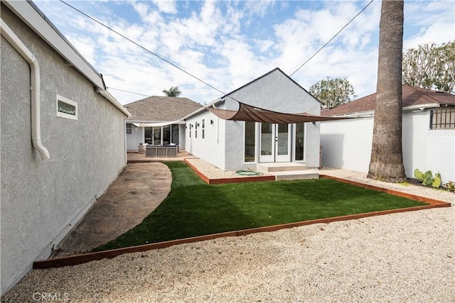 rear view of house featuring a lawn, a patio, fence, french doors, and stucco siding