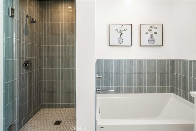 bathroom with a tile shower and a bathtub