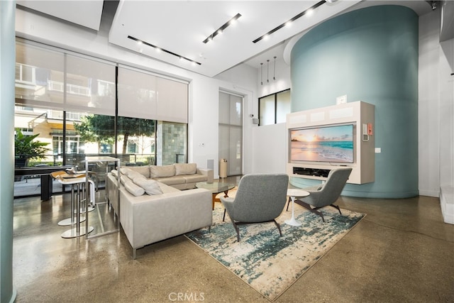 living area with a towering ceiling and track lighting