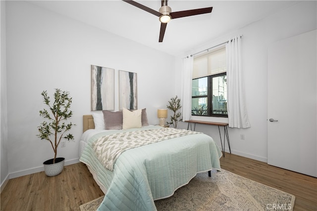 bedroom featuring ceiling fan, baseboards, and wood finished floors