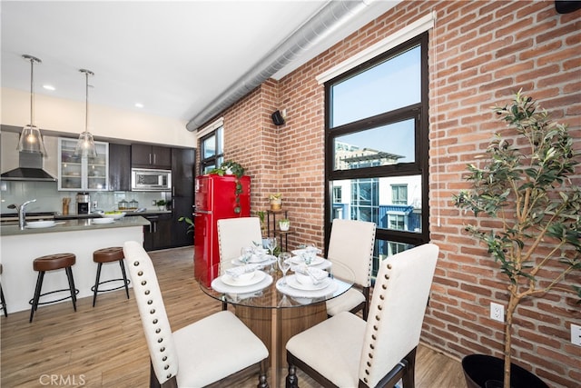 dining room featuring brick wall and light wood-type flooring