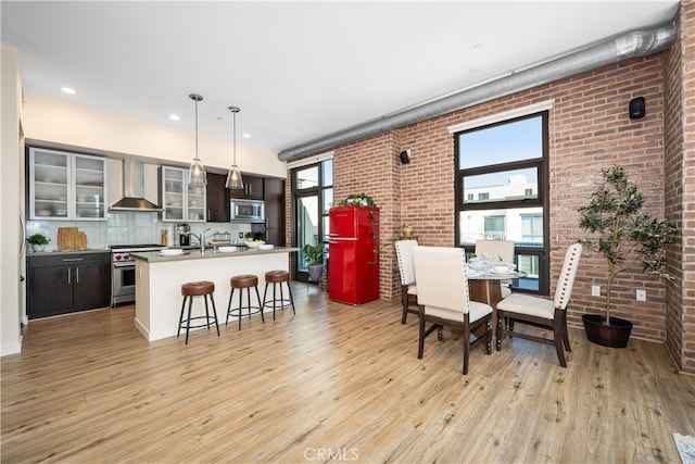 dining area featuring light wood-type flooring and brick wall