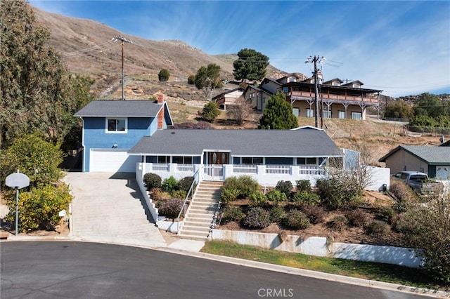 view of front of property featuring a garage, driveway, a porch, and stairs