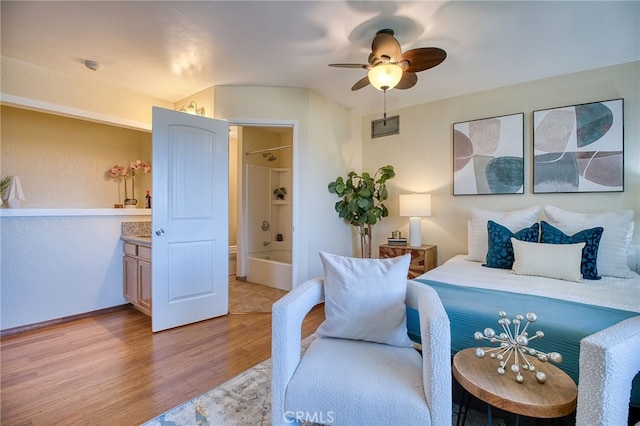 bedroom featuring visible vents, a ceiling fan, light wood-style flooring, and ensuite bathroom