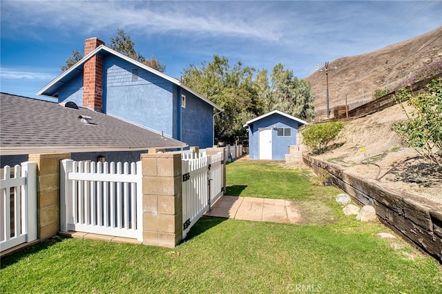 view of yard featuring a storage unit, an outdoor structure, and fence