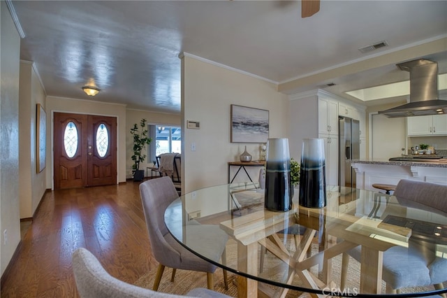 dining area with dark wood-style floors, visible vents, and crown molding