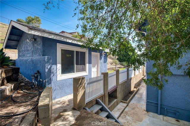 view of side of home with an outbuilding, fence, and stucco siding