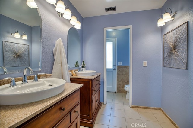 full bathroom with two vanities, tile patterned flooring, visible vents, and a sink