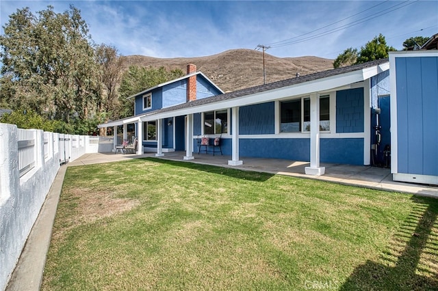 rear view of property featuring a yard, a patio area, a fenced backyard, and a mountain view