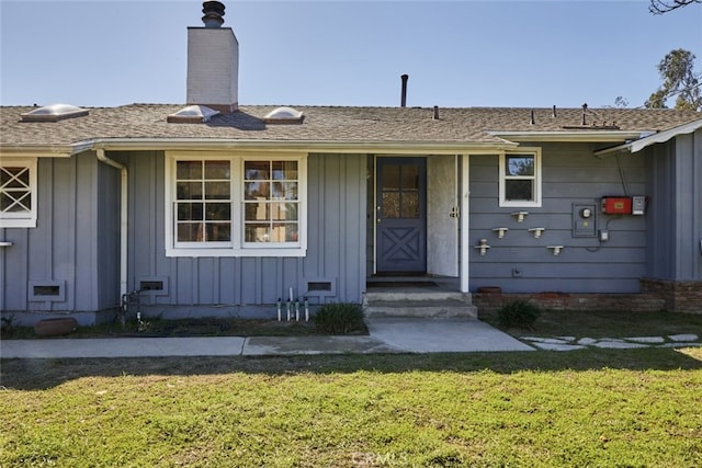 doorway to property featuring a yard, board and batten siding, and a chimney