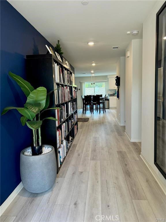 corridor featuring light wood-style flooring, visible vents, and baseboards