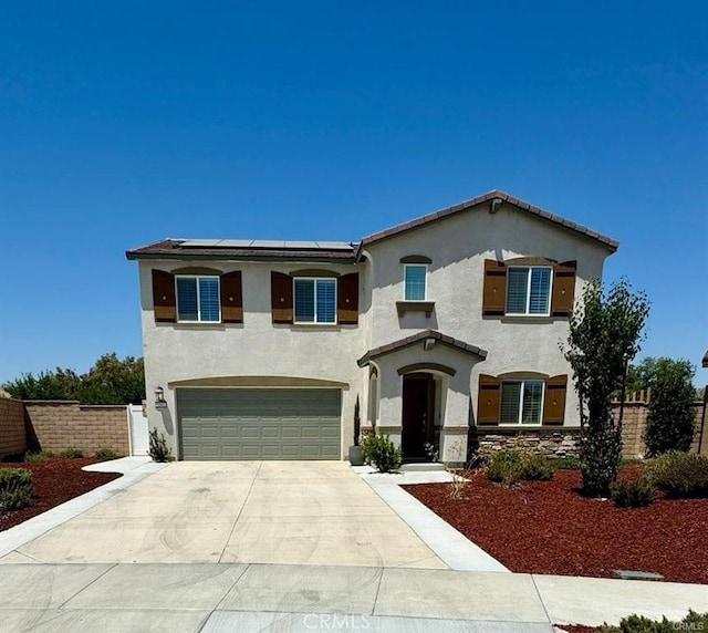 mediterranean / spanish house featuring roof mounted solar panels, driveway, fence, and stucco siding