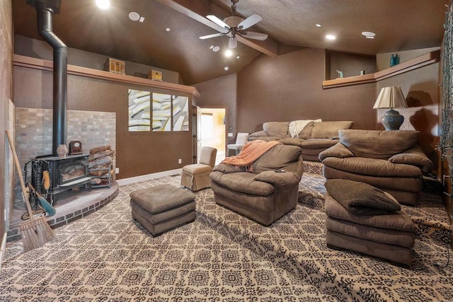 carpeted cinema featuring a wood stove, vaulted ceiling with beams, baseboards, and ceiling fan