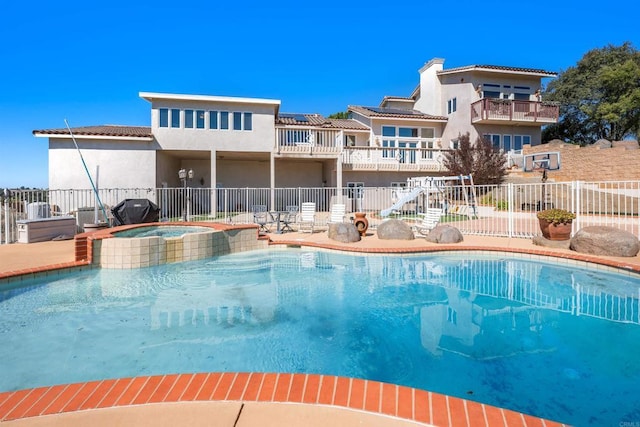 view of pool with a patio, area for grilling, fence, and a pool with connected hot tub