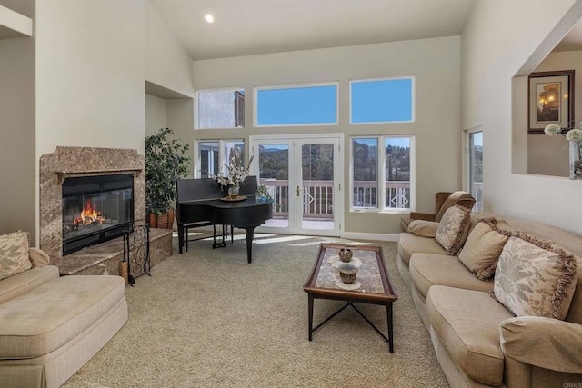 carpeted living room featuring a high ceiling, a glass covered fireplace, a wealth of natural light, and french doors