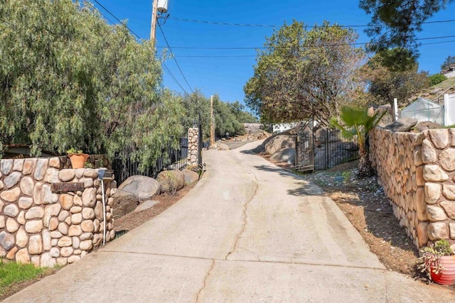 view of street featuring concrete driveway and a gated entry