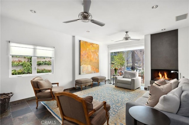 sitting room featuring recessed lighting, stone tile floors, visible vents, baseboards, and a lit fireplace