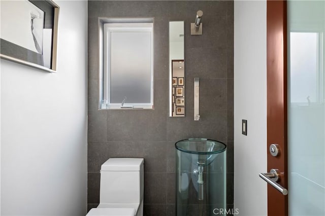 bathroom featuring toilet and tile walls